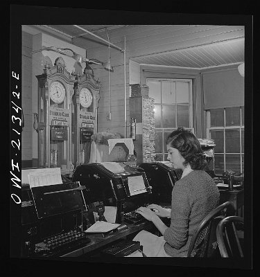 1943 Seligman, Arizona. Teletype operator in the telegraph office of the Atchison, Topeka, and Santa Fe Railroad. The time here changes from Mountain to Pacific time